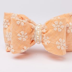 Peach headband with daisy-embroidered bow and faux pearl strand for girls