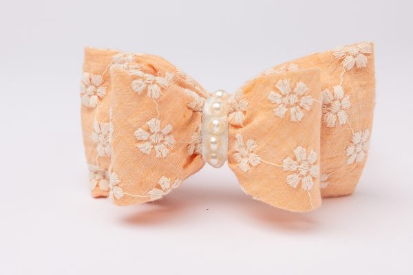 Peach headband with daisy-embroidered bow and faux pearl strand for girls