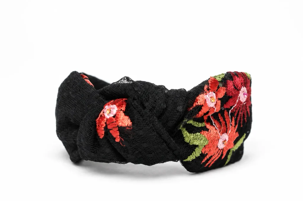 Black embroidered headband with colourful floral embroidery, featuring red, coral, pink, and green flower and leaf details.