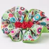 Lime green headband with ruffled colourful dot-print flower and red rosettes for girls. flower headband