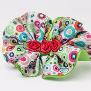Lime green headband with ruffled colourful dot-print flower and red rosettes for girls. flower headband