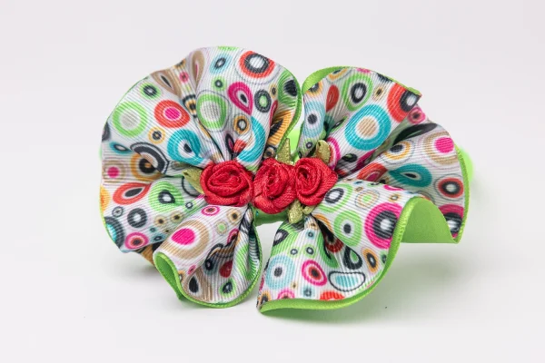Lime green headband with ruffled colourful dot-print flower and red rosettes for girls. flower headband